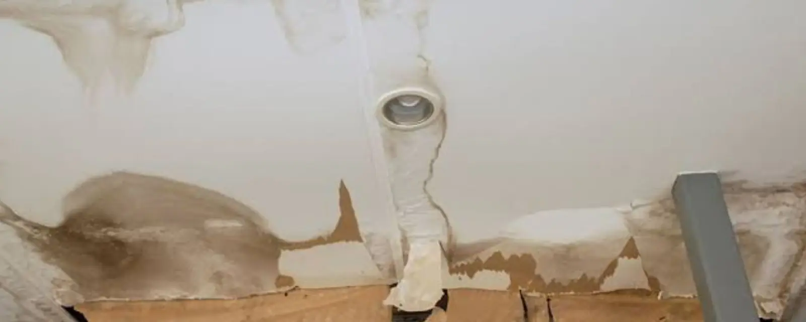 Water-damaged ceiling with sagging drywall and brown stains