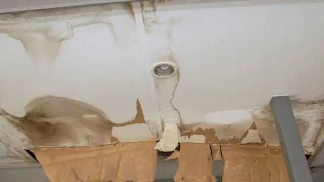 Water-damaged ceiling with sagging drywall and brown stains