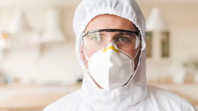 Contractor in a hood, goggles and respirator mask